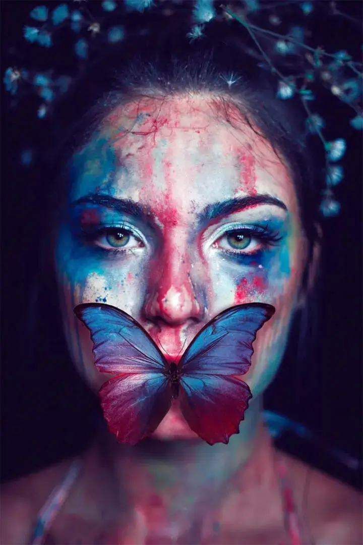 Portrait of a woman with colors of face and butterfly on her lips