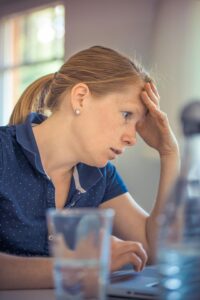 woman with hand over forehead looking anxious | Therapy for Anxiety