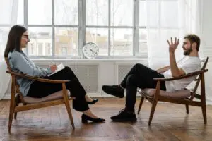 Man in woman sitting in chairs across from each other talking | Bay Area Counseling and Consulting